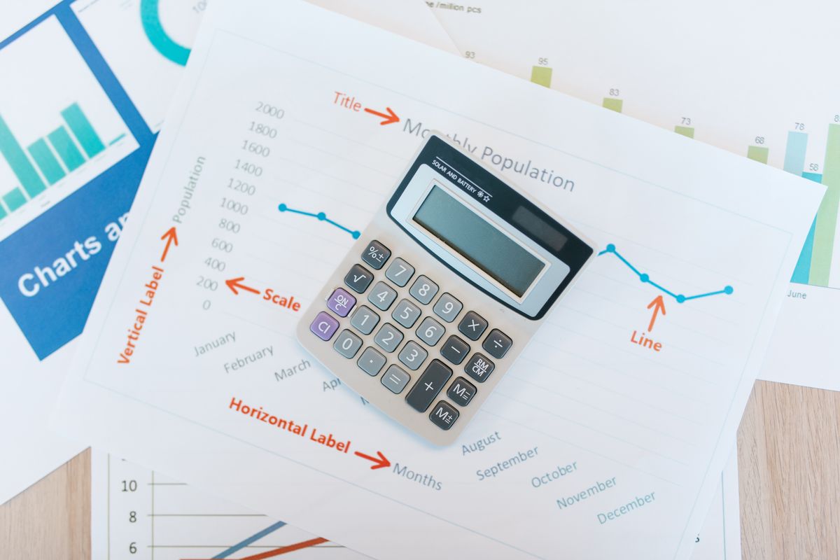 A calculator placed over printed charts and analytical reports